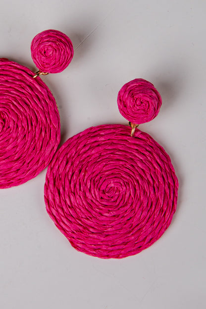 Pink woven earrings on a light gray background