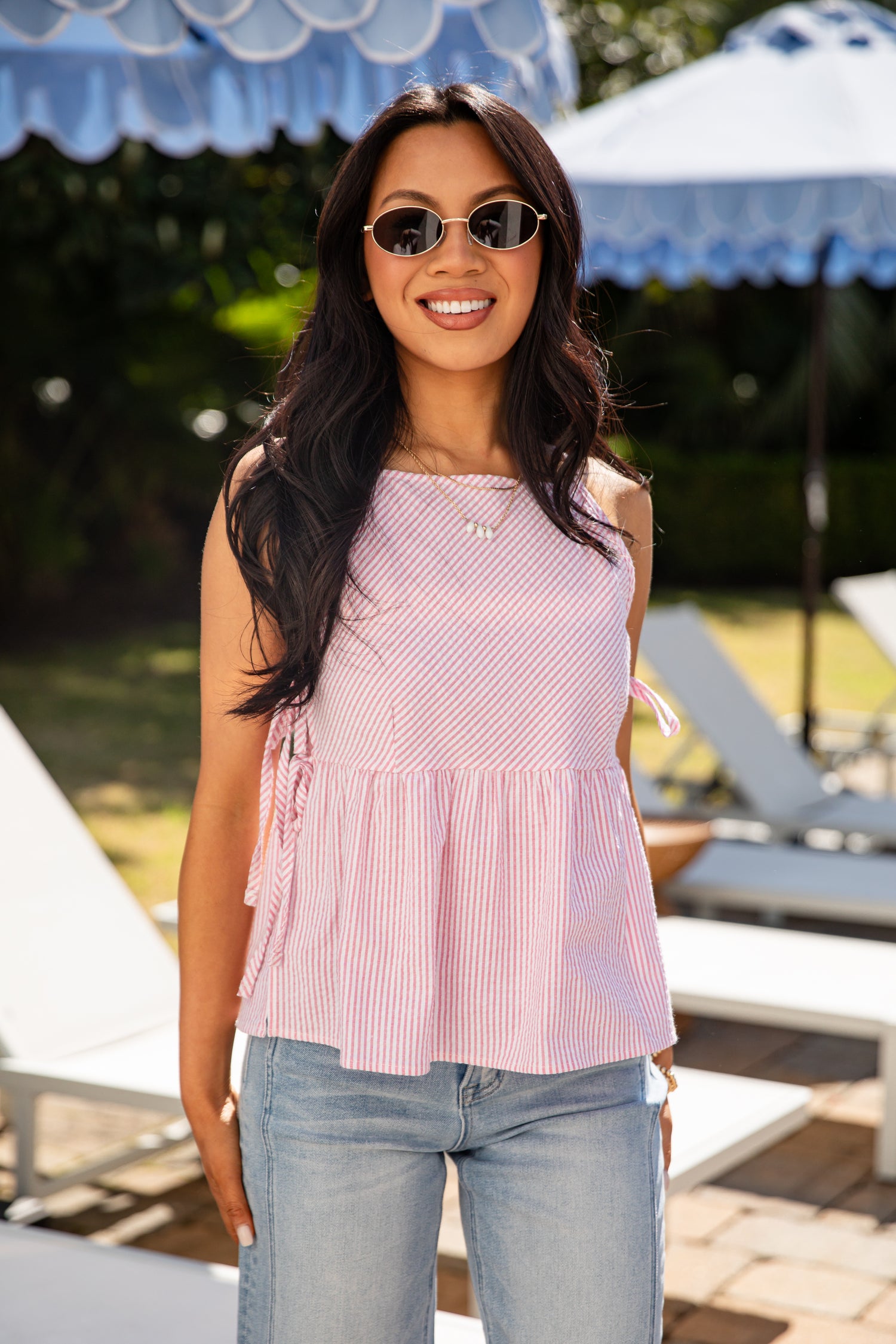 Woman wearing a pink sleeveless top and sunglasses outdoors