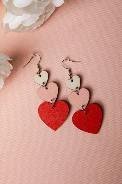 Heart-shaped earrings on a pink background with white flowers.