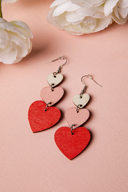Heart-shaped earrings on a pink surface with white flowers