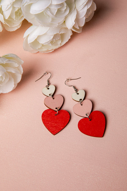 Heart-shaped earrings on a pink surface with white flowers