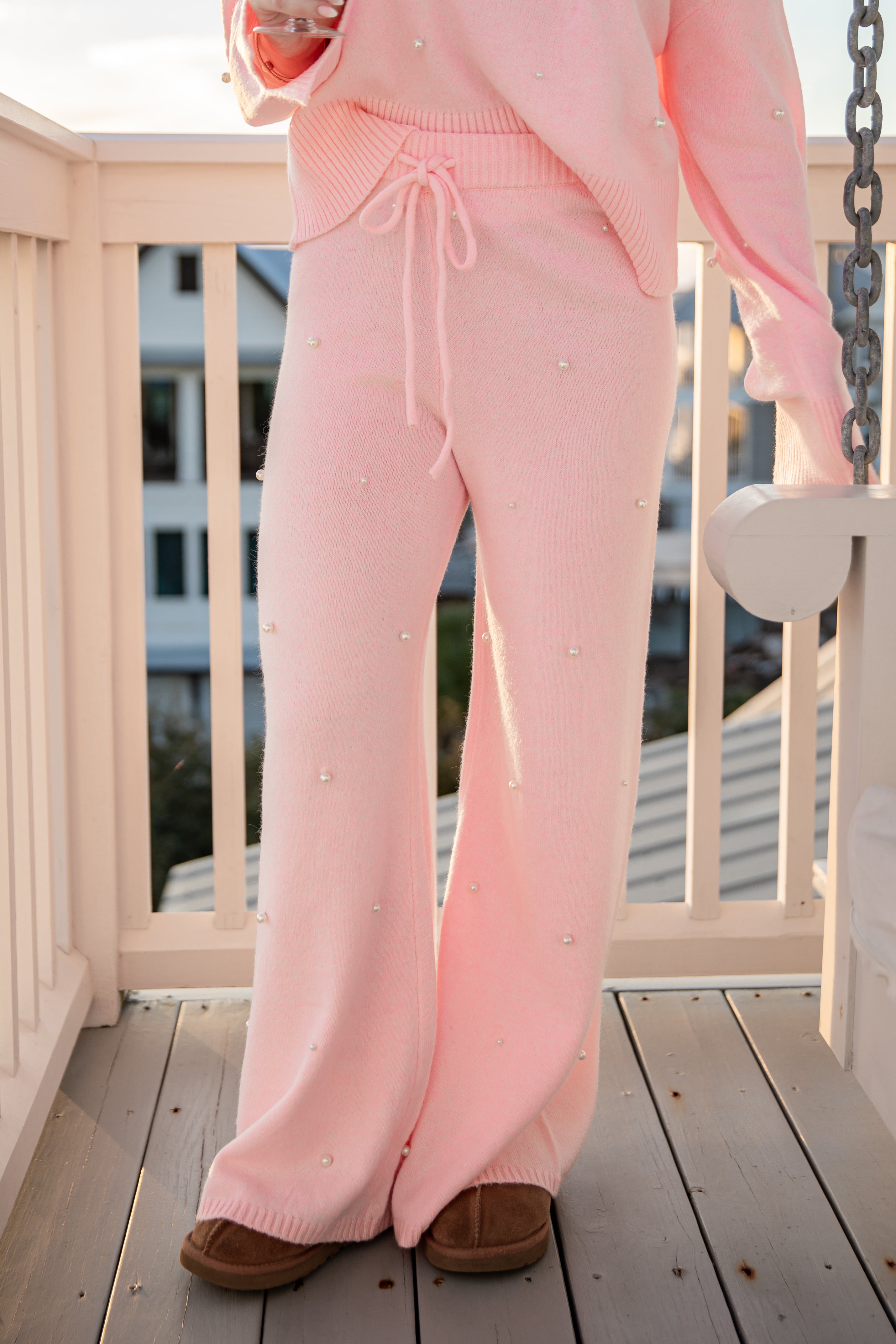 Person wearing a pink outfit with white polka dots on a wooden deck.
