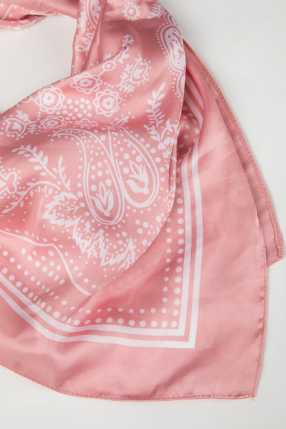 Pink bandana with white paisley pattern on a light gray background