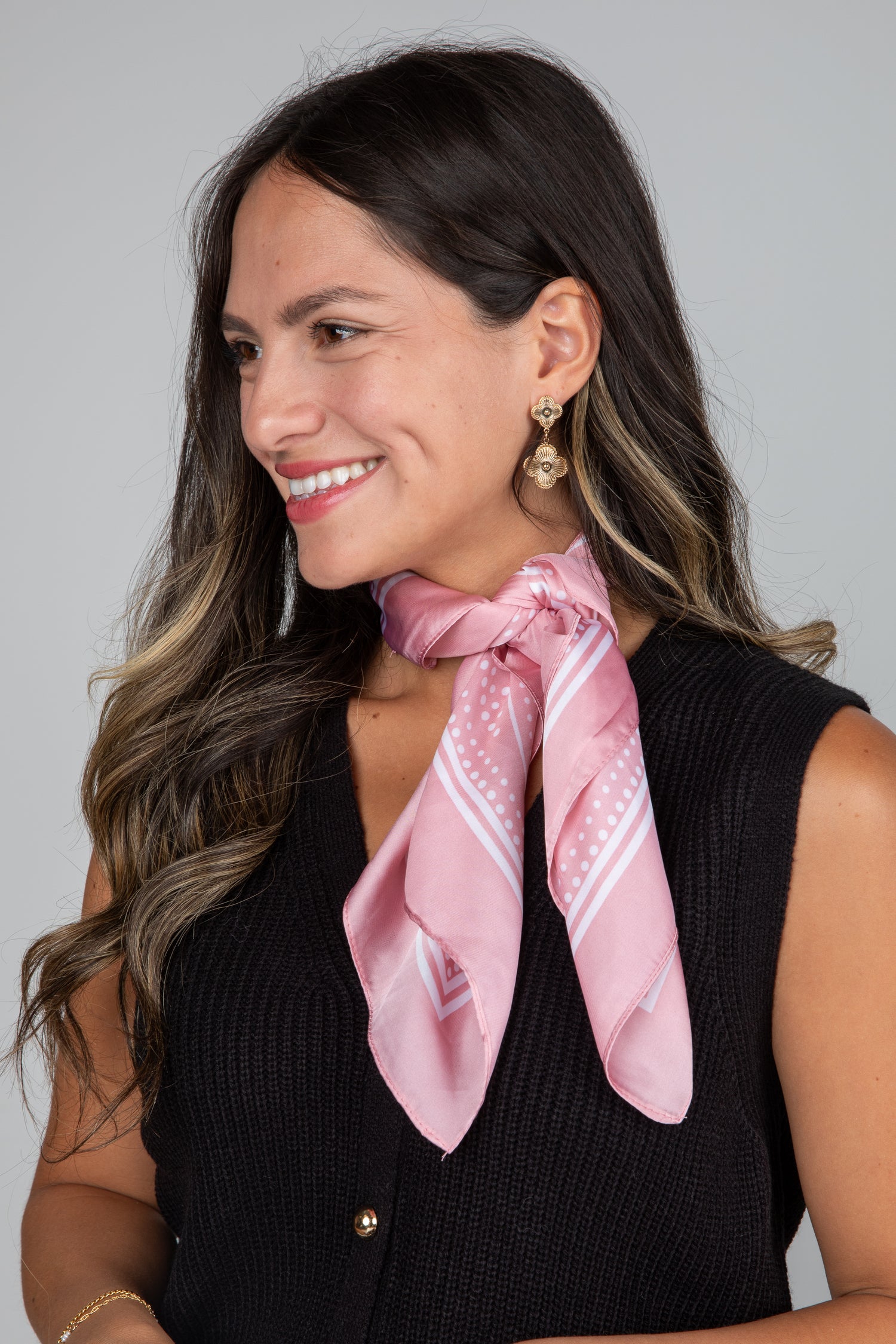 Woman wearing a pink scarf with a subtle pattern on a plain background