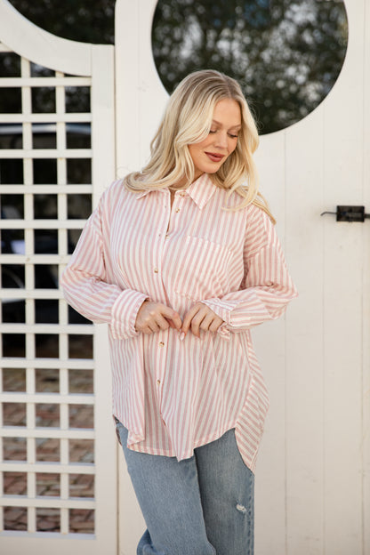 Woman wearing a pink and white striped shirt in front of a white door with circular window