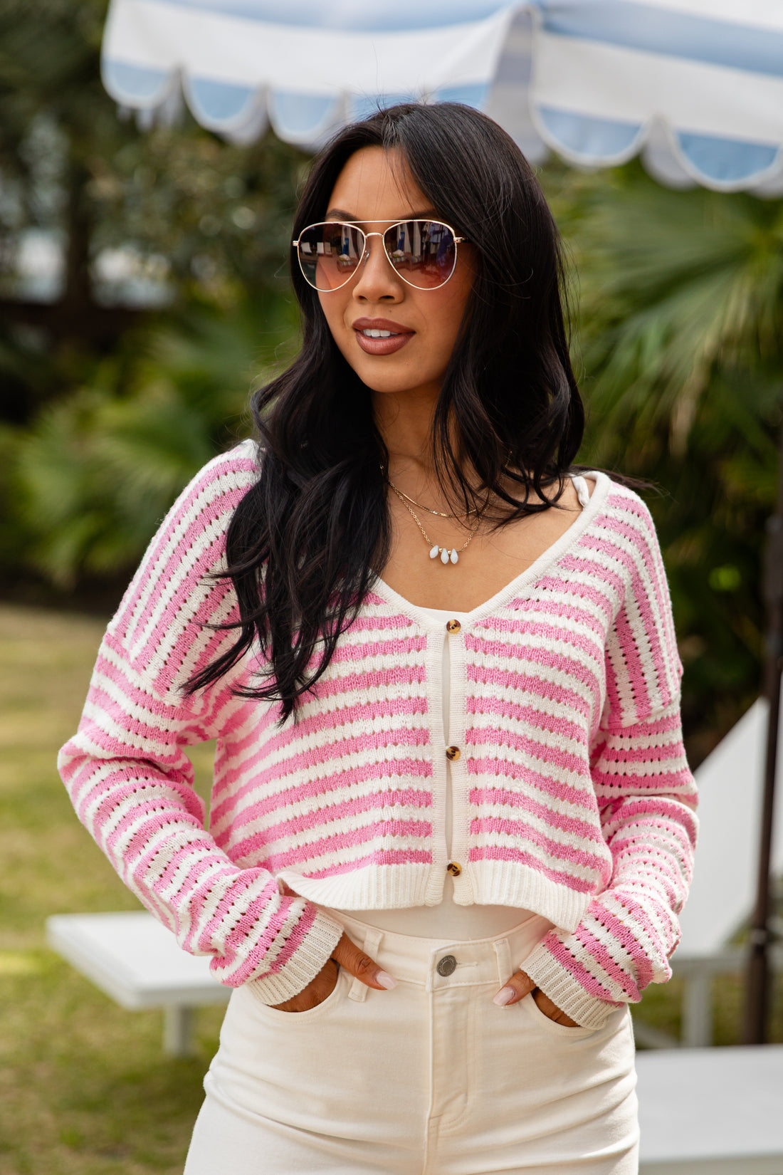 Woman wearing a pink and white striped cardigan outdoors