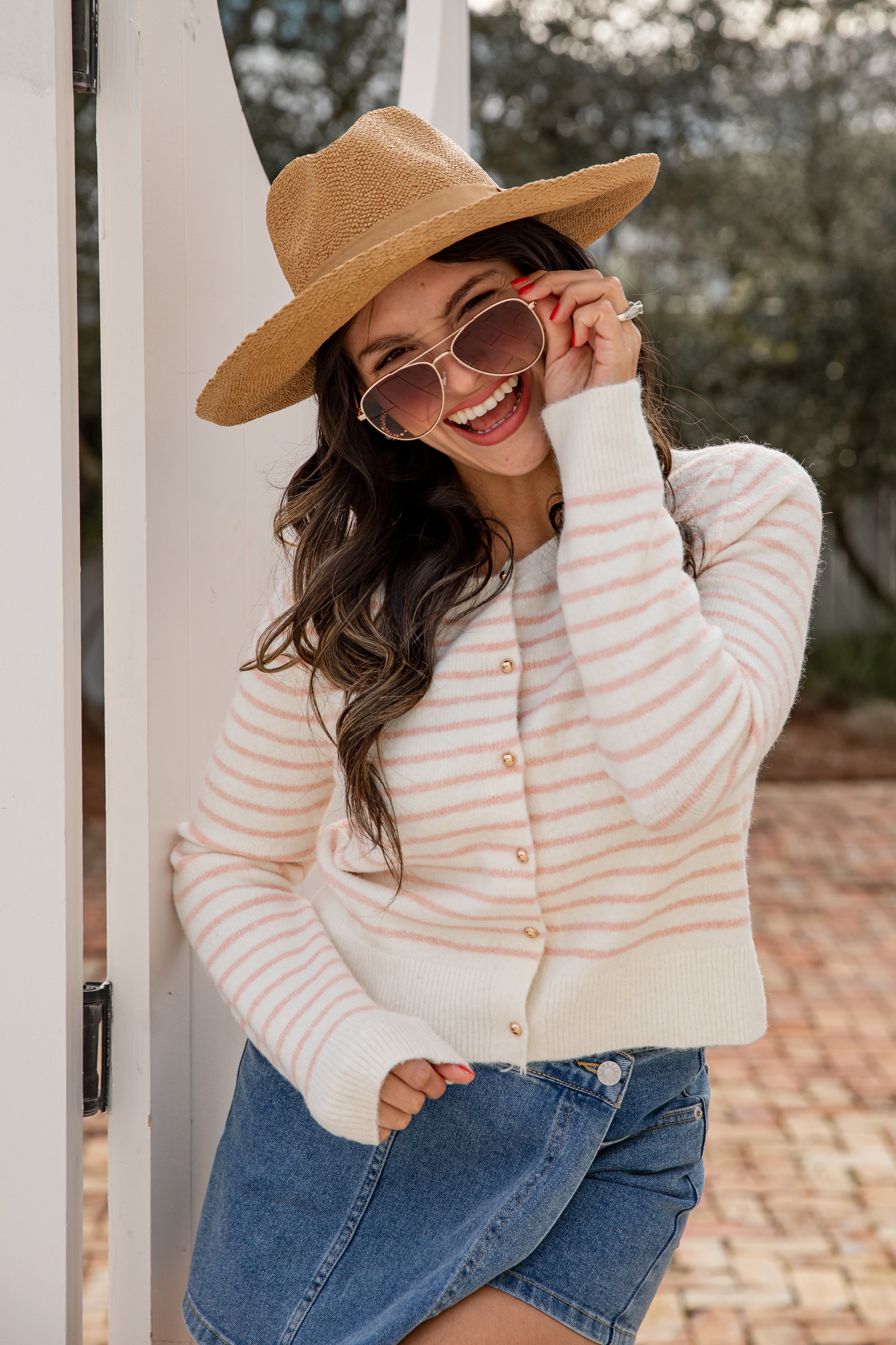 Woman wearing a beige hat and striped sweater, standing outdoors.