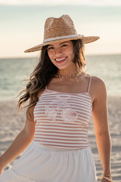 Woman wearing a striped tank top and straw hat on a beach