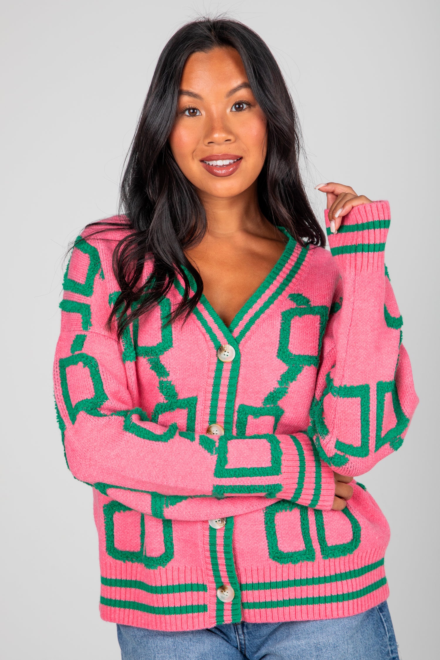 Woman wearing a pink and green patterned cardigan against a gray background