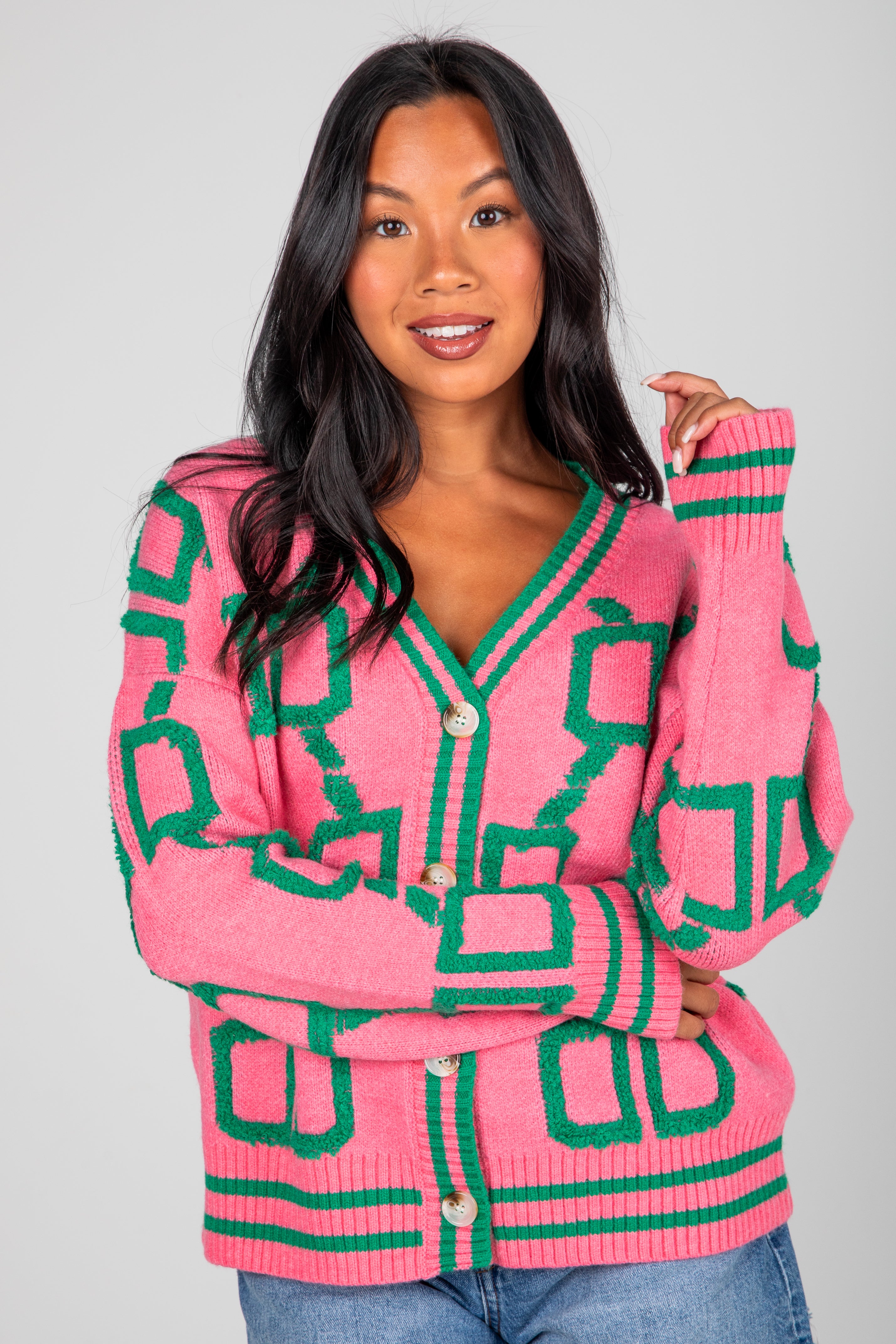 Woman wearing a pink and green patterned cardigan against a gray background