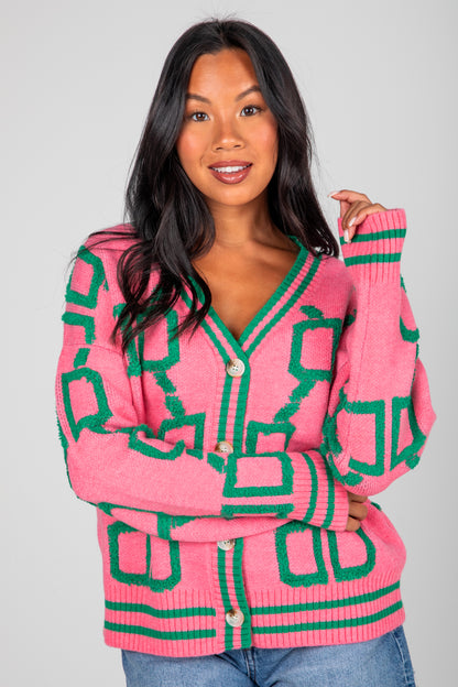 Woman wearing a pink and green patterned cardigan against a gray background