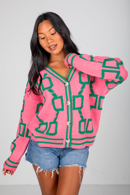 Woman wearing a pink and green patterned cardigan against a plain background