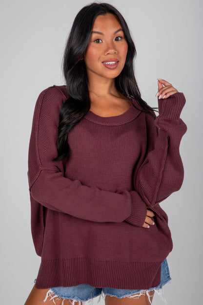 Woman wearing a burgundy sweater with a plain background