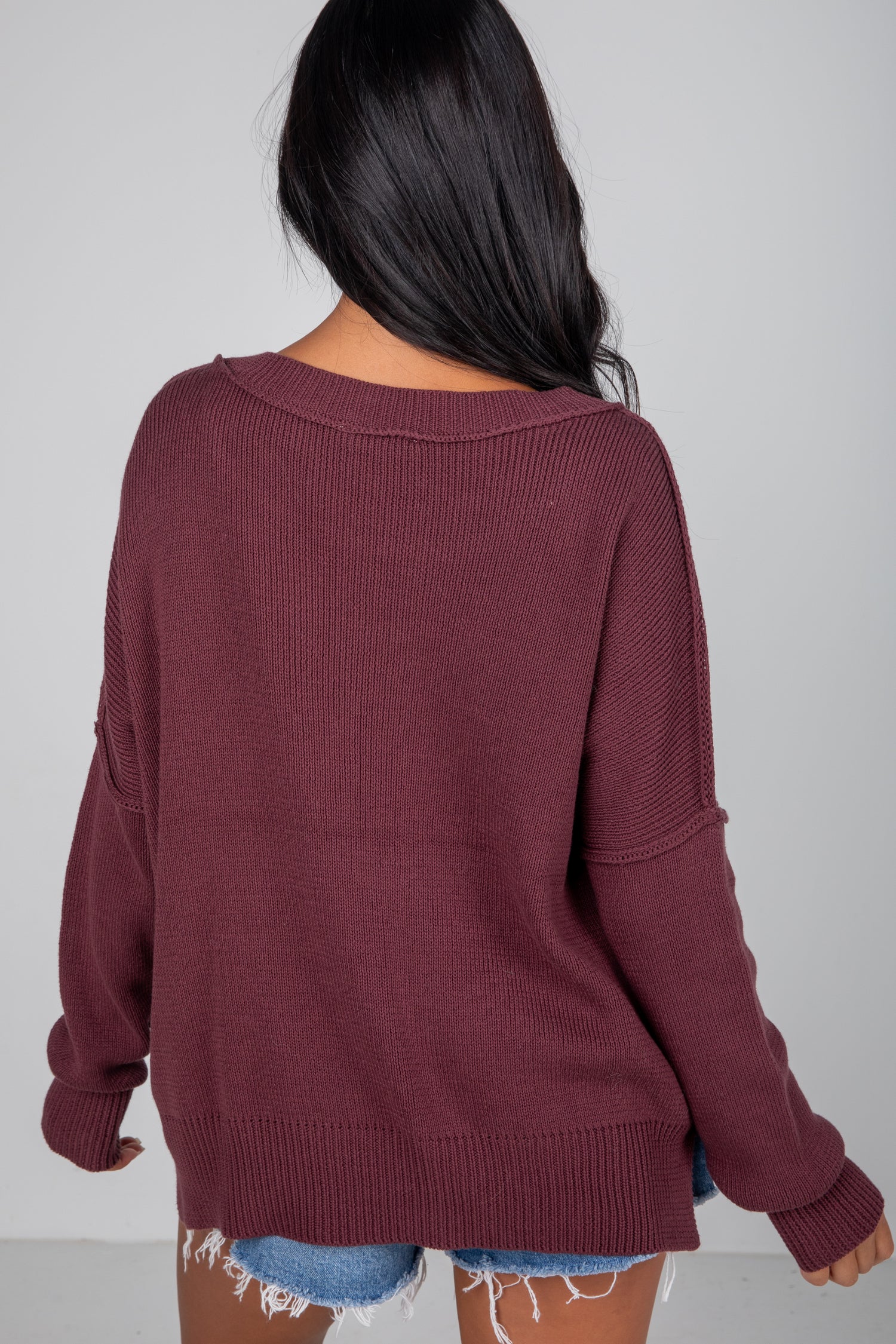 Person wearing a maroon sweater with a plain background