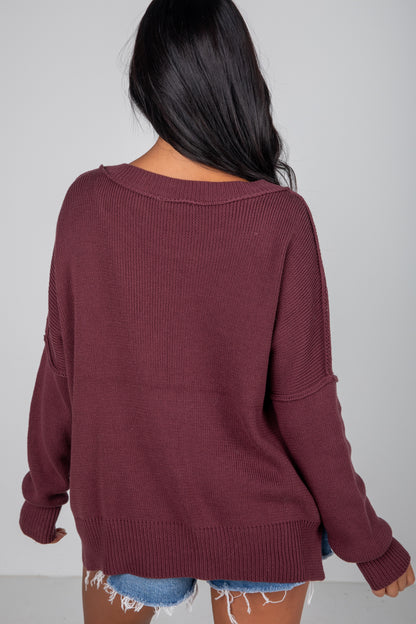 Person wearing a maroon sweater with a plain background