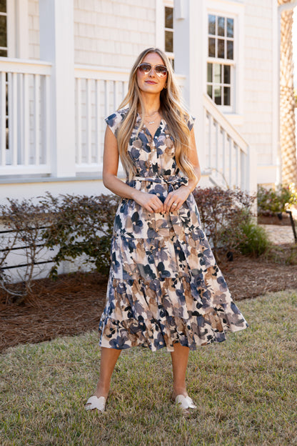 Woman in a floral dress standing in front of a white house.