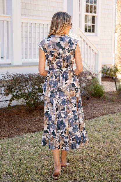 Woman wearing a floral dress standing in front of a house.
