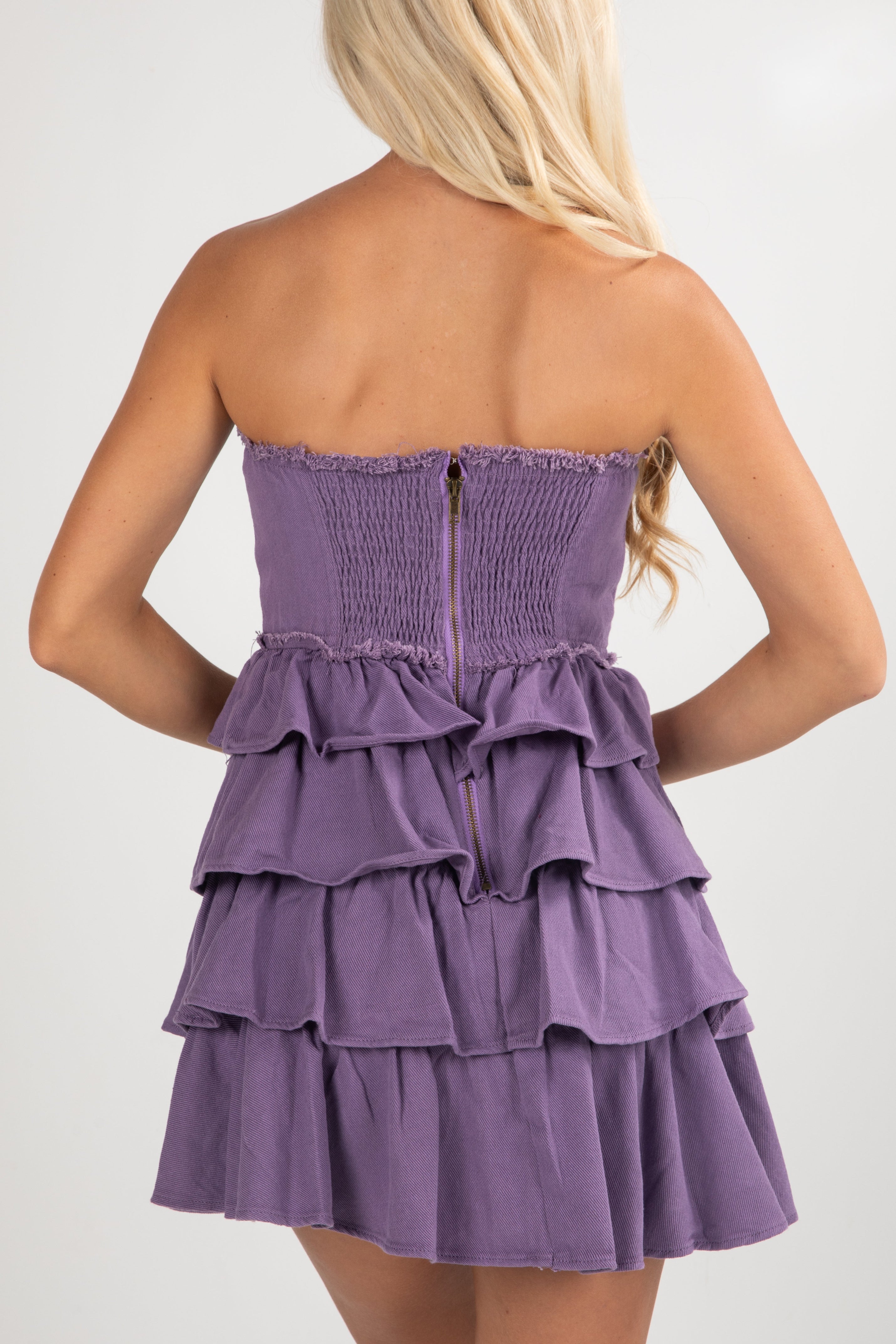 Purple strapless dress with ruffled layers on a white background