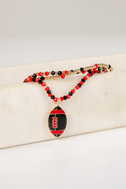 Necklace with football pendant and red and black beads on a white surface