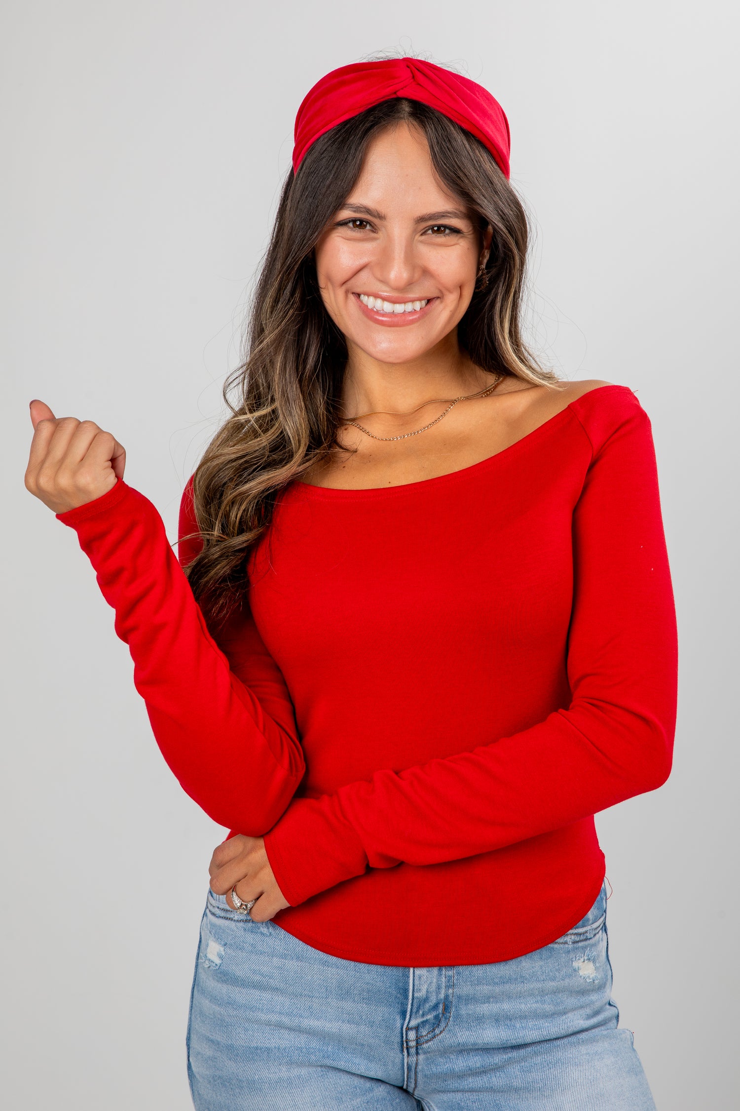 Woman wearing a red sweater and headband against a gray background
