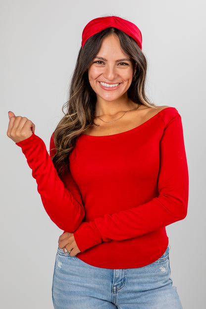 Woman wearing a red sweater and headband against a gray background