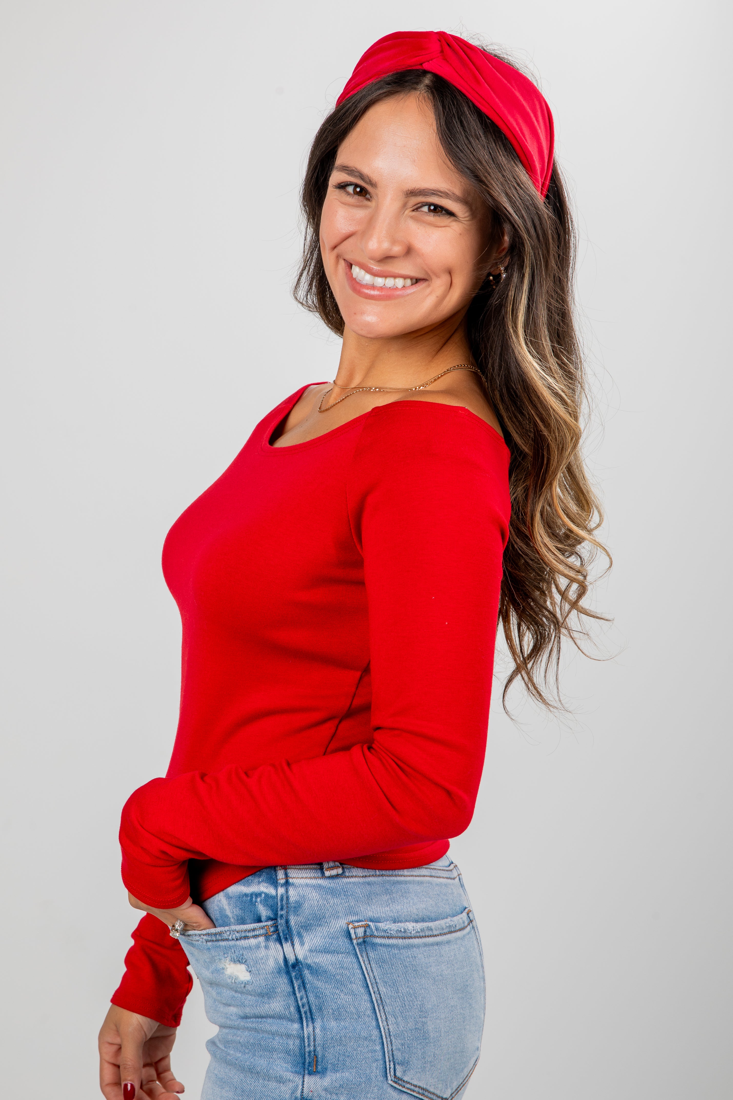 Woman wearing a red sweater and headband against a gray background