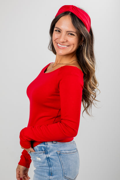 Woman wearing a red sweater and headband against a gray background