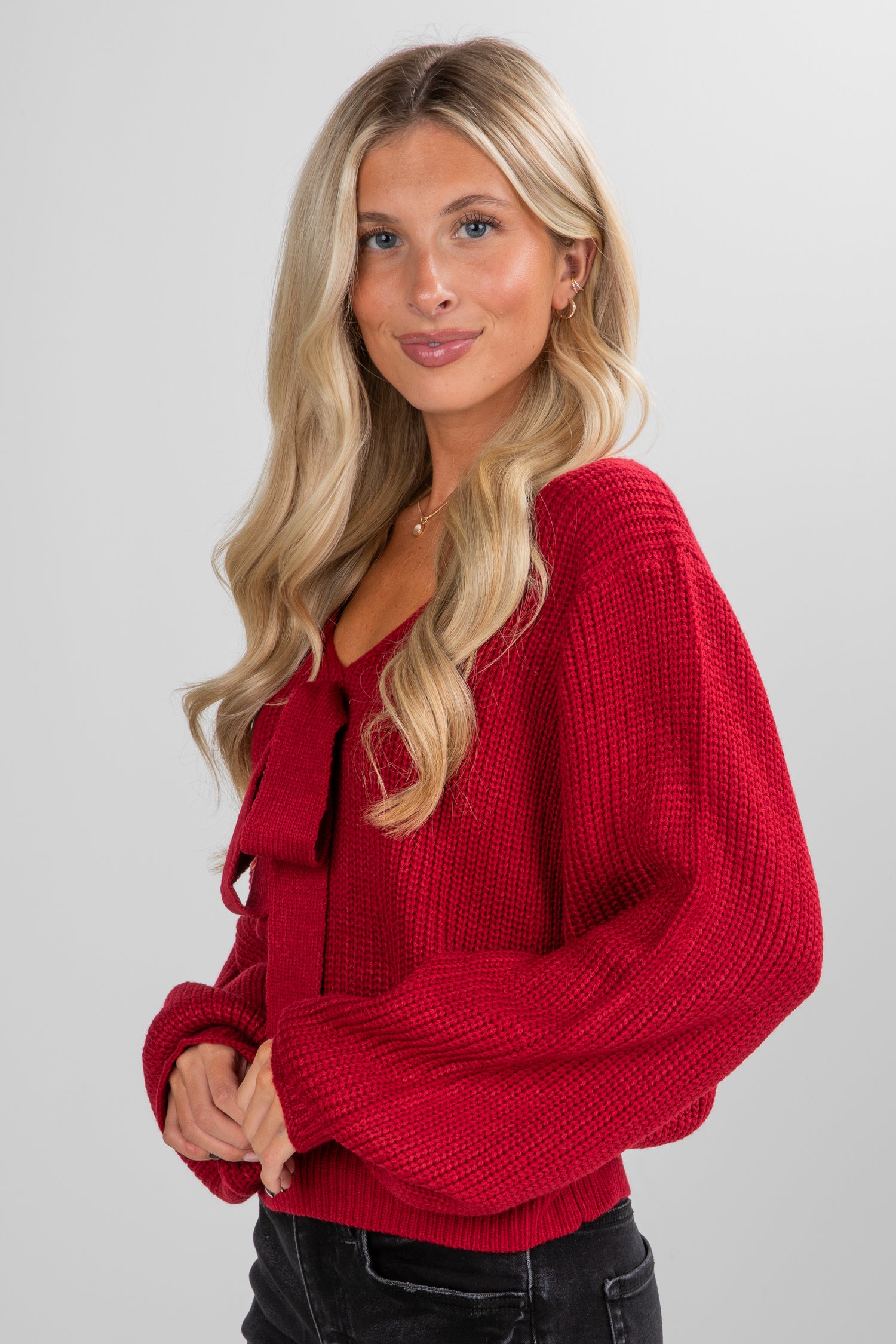 Woman wearing a red sweater against a plain background
