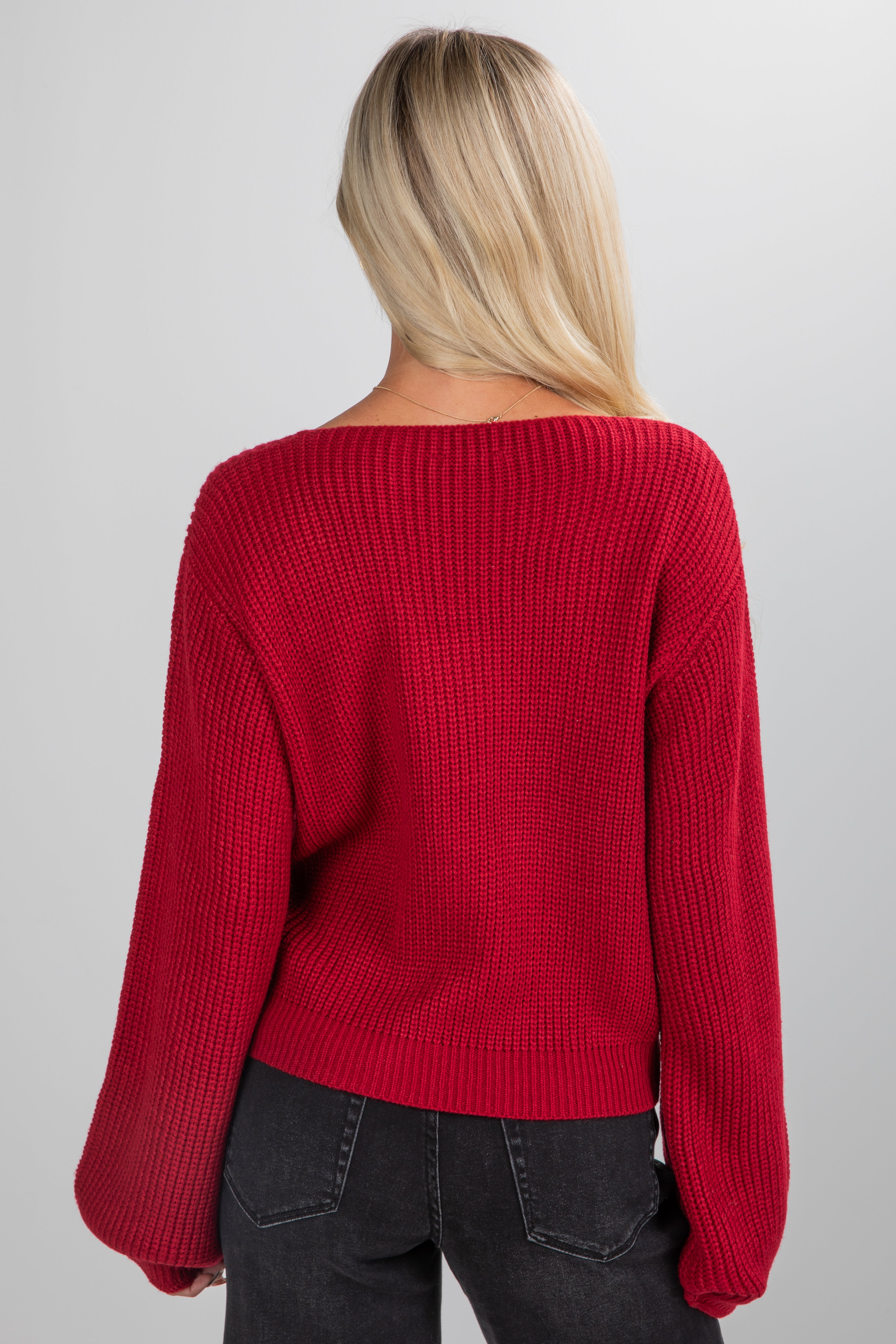 Person wearing a red sweater on a plain background