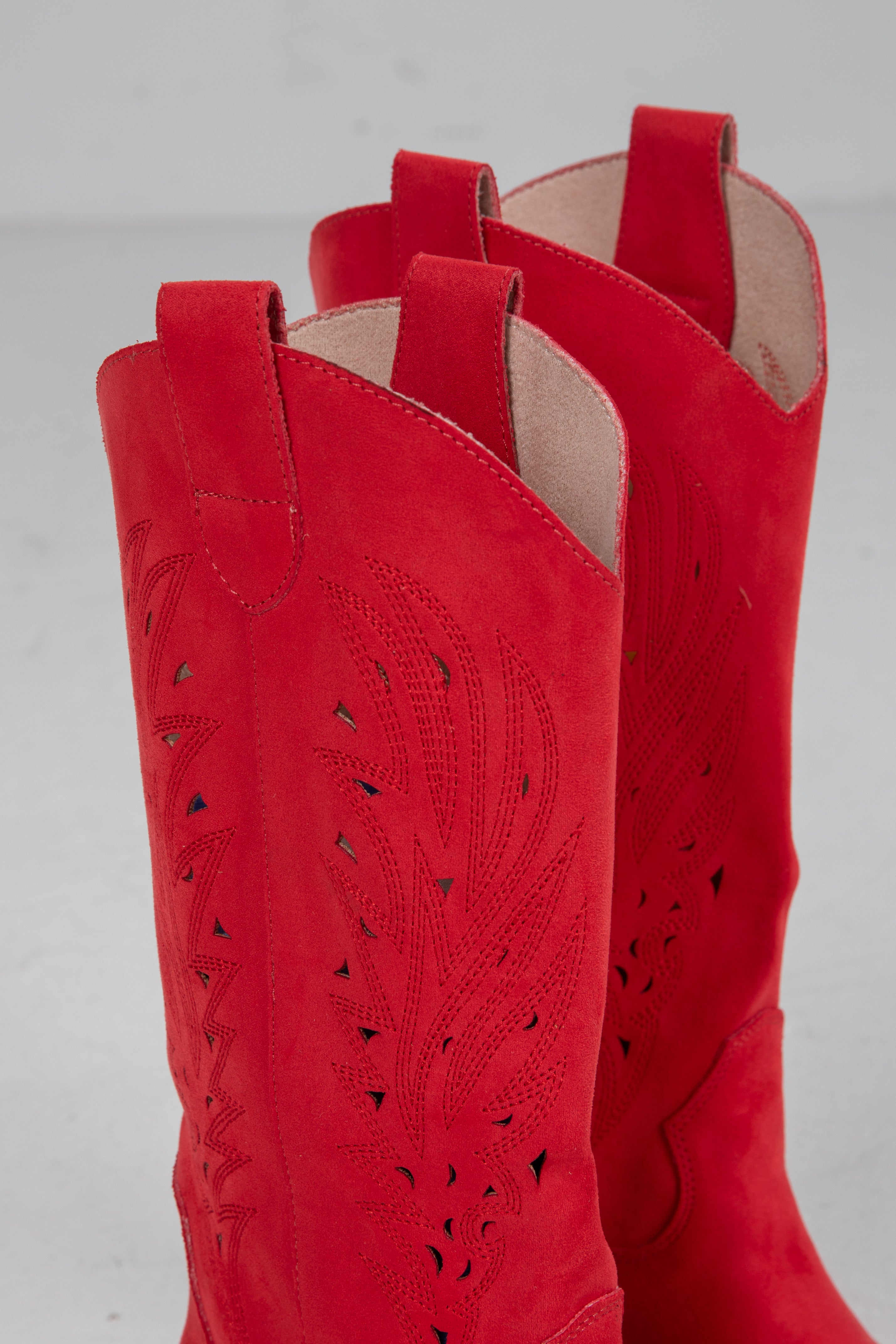 Close-up of red cowboy boots with cut-out design on a gray background