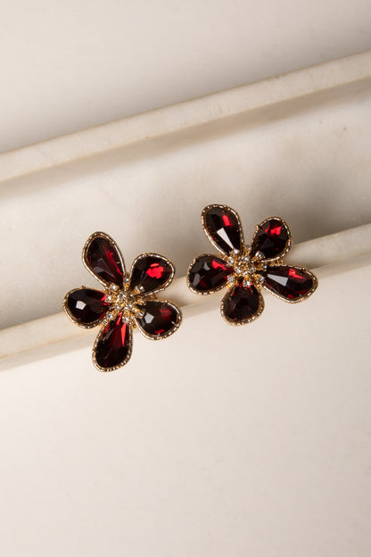 Flower-shaped earrings with red gemstones on a light background