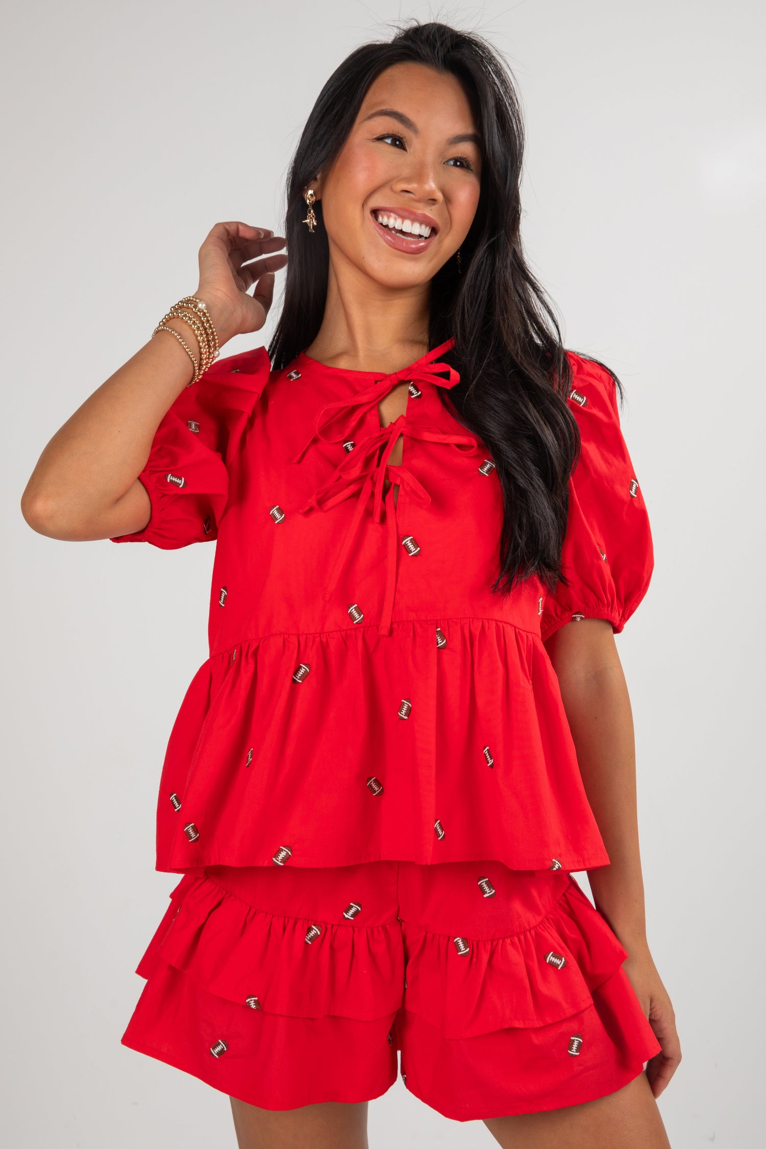 Woman wearing a red dress with puff sleeves and layered skirt on a white background