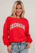 A blonde woman wearing a bright red crewneck sweatshirt with &