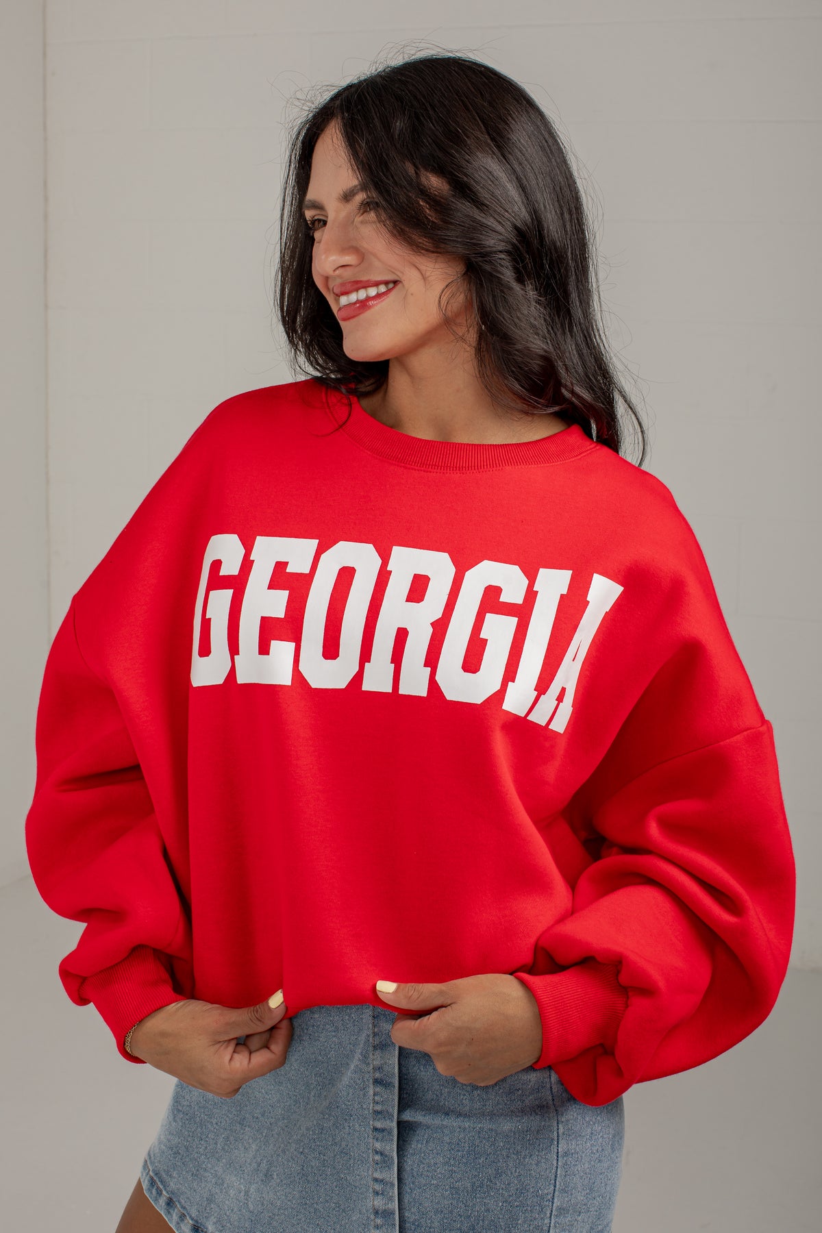 A woman wearing a bright red crewneck sweatshirt with &