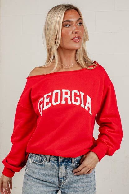 A woman wearing a bright red off-the-shoulder sweatshirt with &
