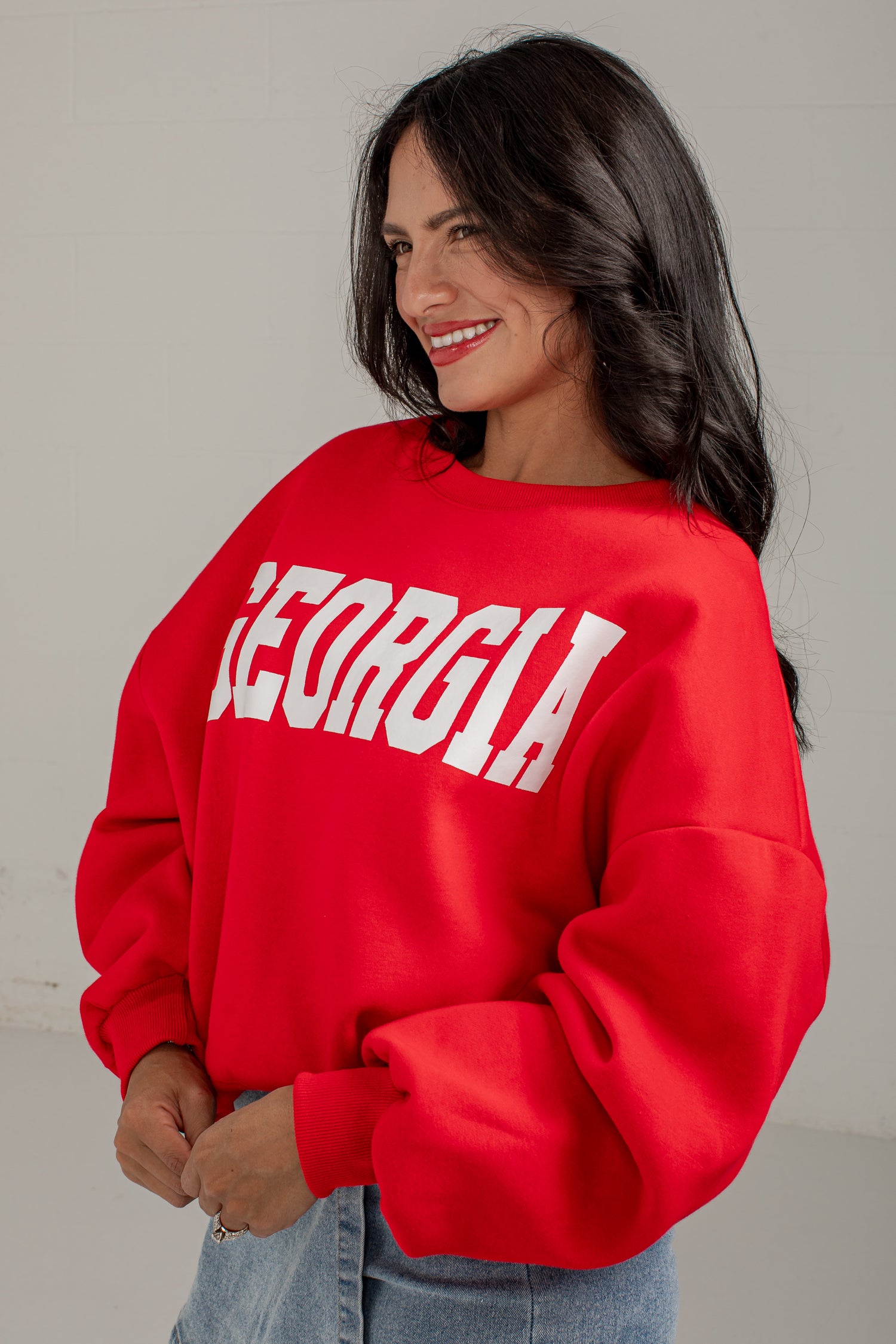 A woman wearing a bright red crewneck sweatshirt with &