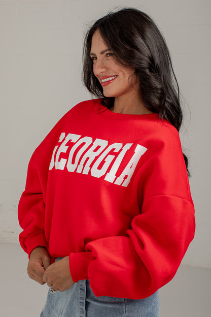A woman wearing a bright red crewneck sweatshirt with &