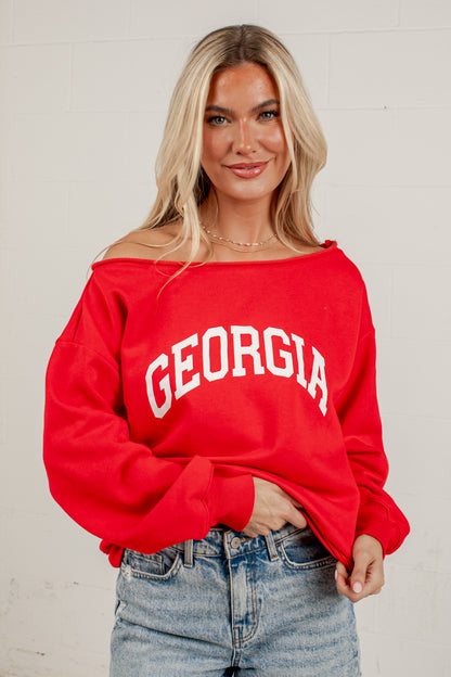 A woman wearing a bright red off-the-shoulder sweatshirt with &