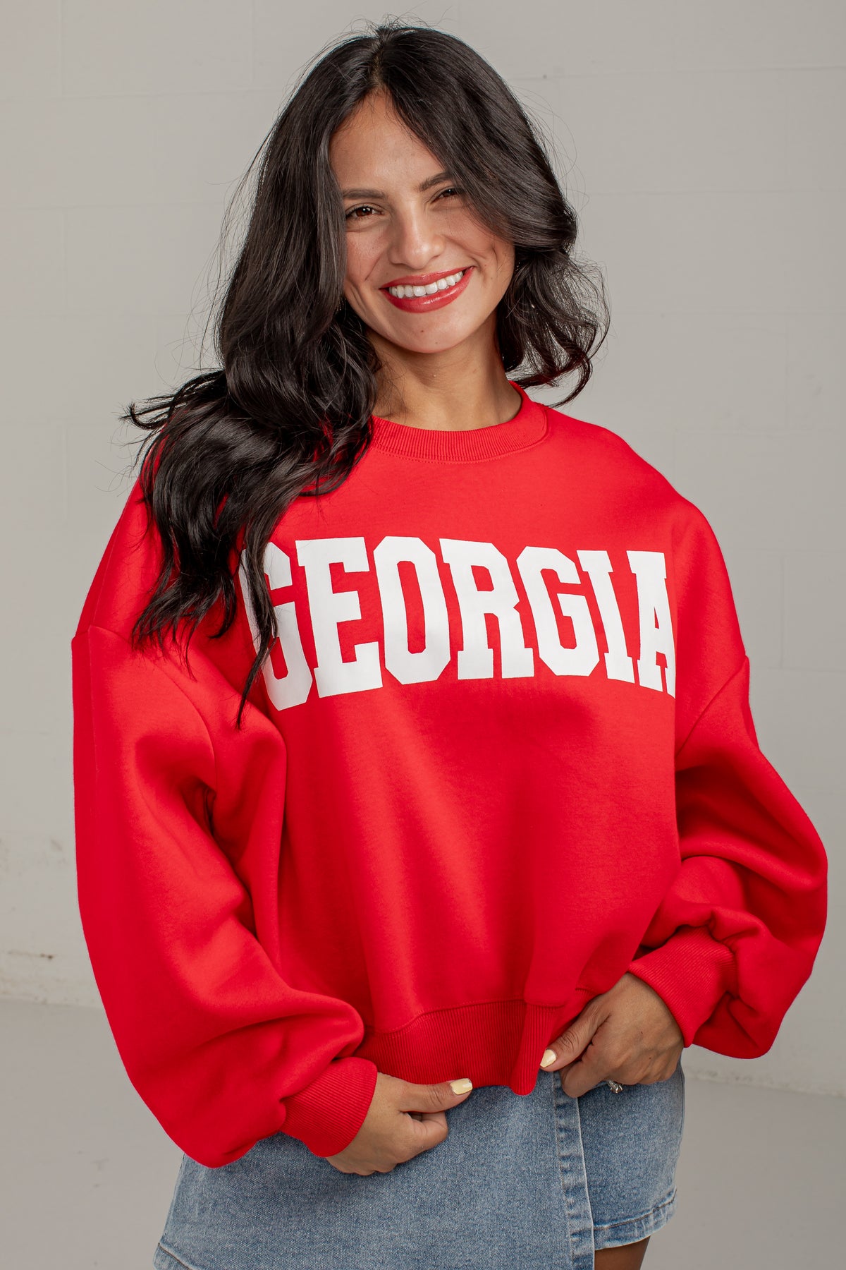 A woman wearing a bright red crewneck sweatshirt with &