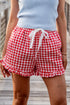 Person wearing red and white checkered shorts with a drawstring on a wooden deck.