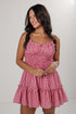 A woman wearing a red and white gingham mini dress with a smocked bodice and ruffled straps, posing against a light gray studio background.
