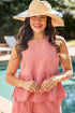 Woman wearing a red checkered dress and straw hat by a pool