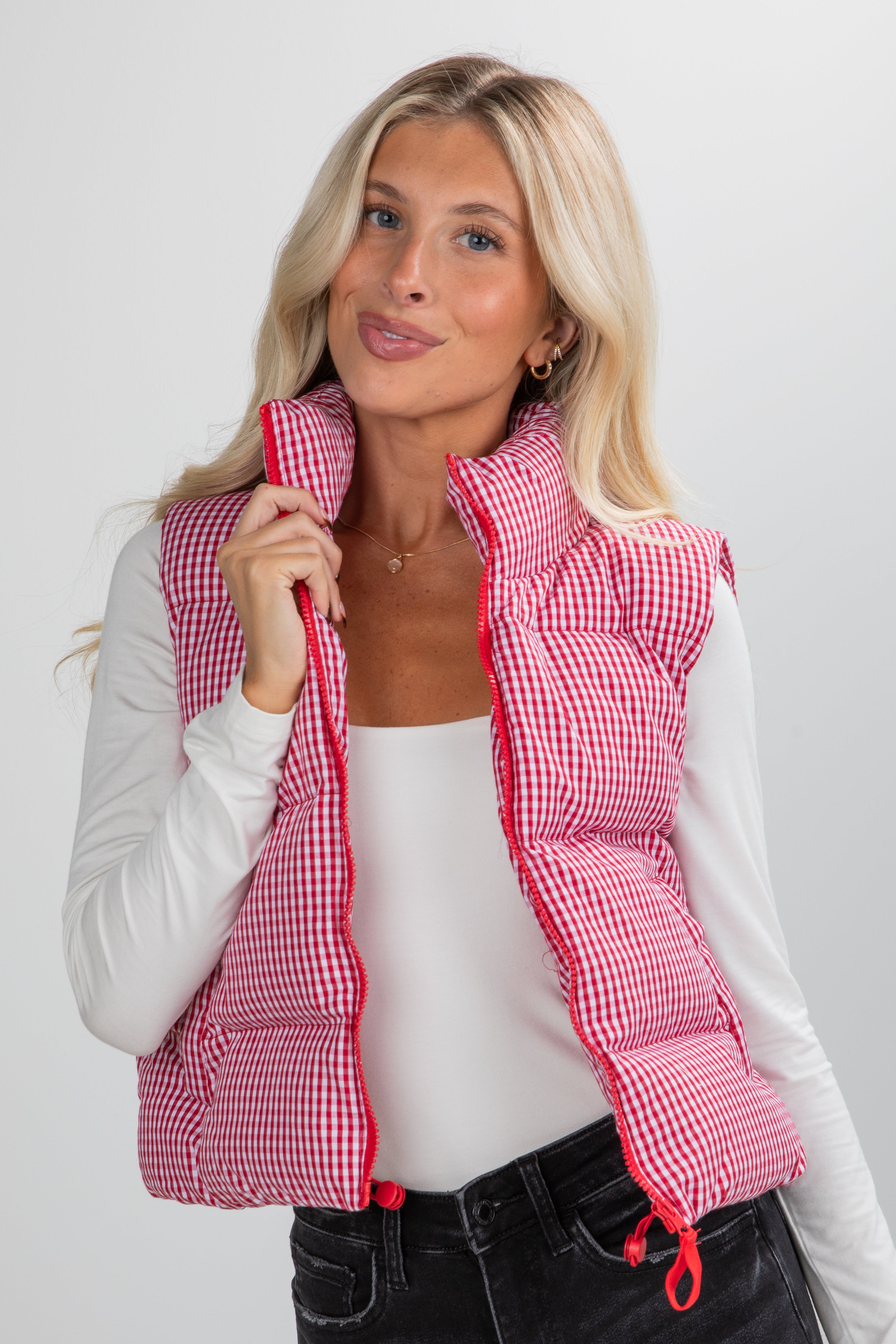 Woman wearing a red and white checkered vest on a plain background