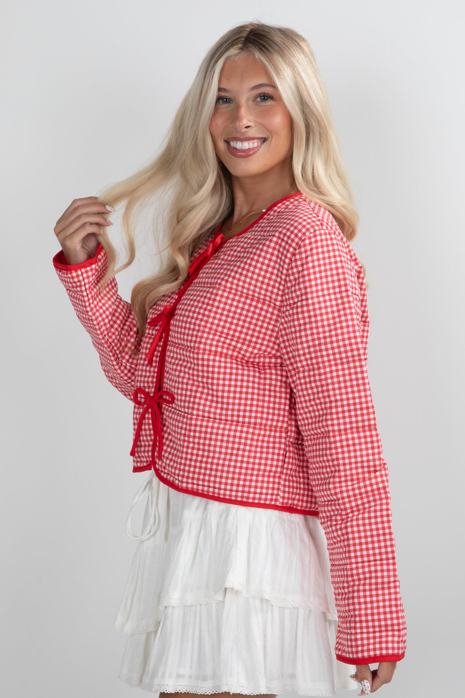 Woman wearing a red and white checkered top with a white skirt on a plain background