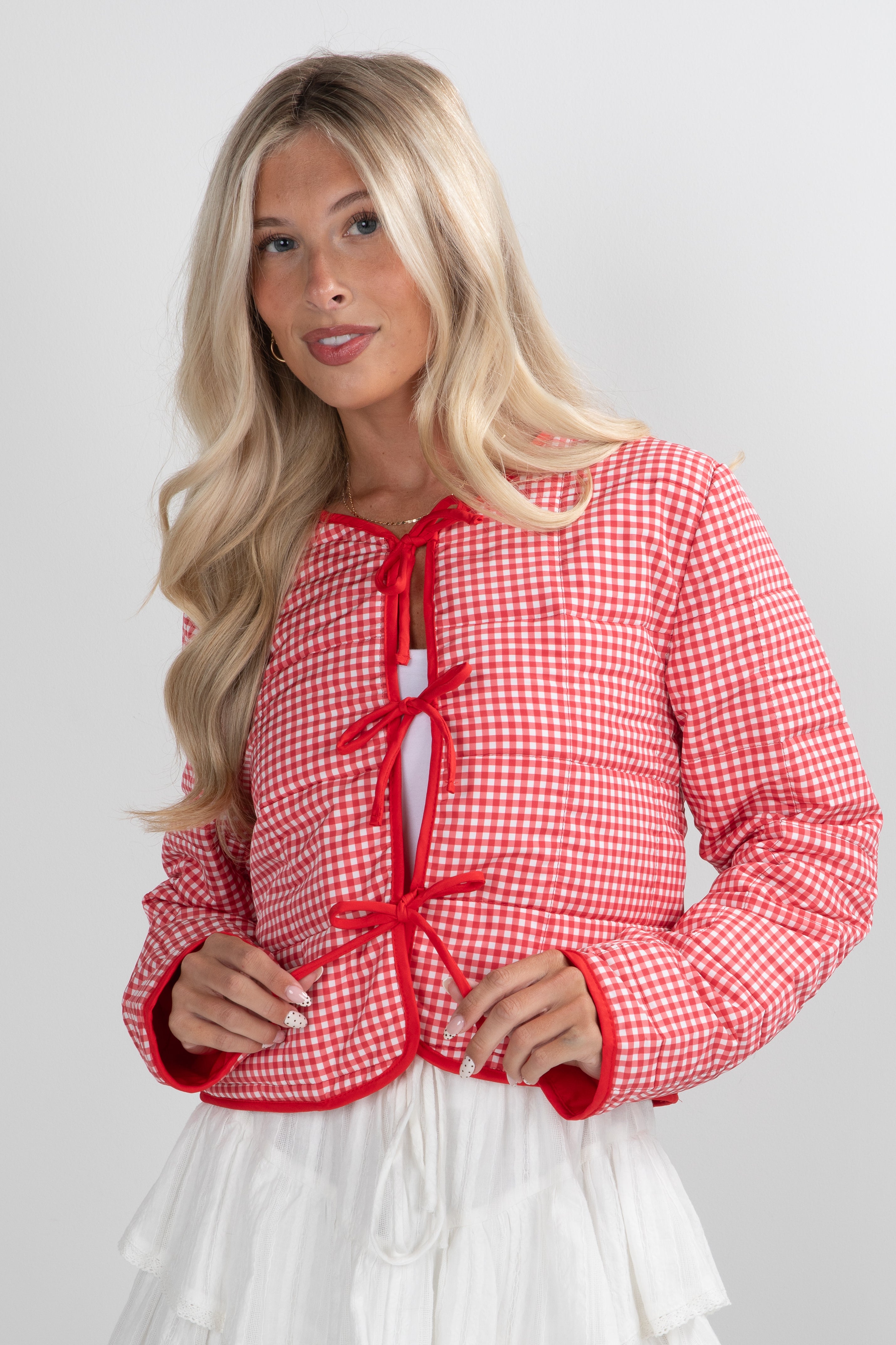 Woman wearing a red and white checkered jacket on a plain background