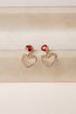 Heart-shaped earrings with red gemstones on a beige background
