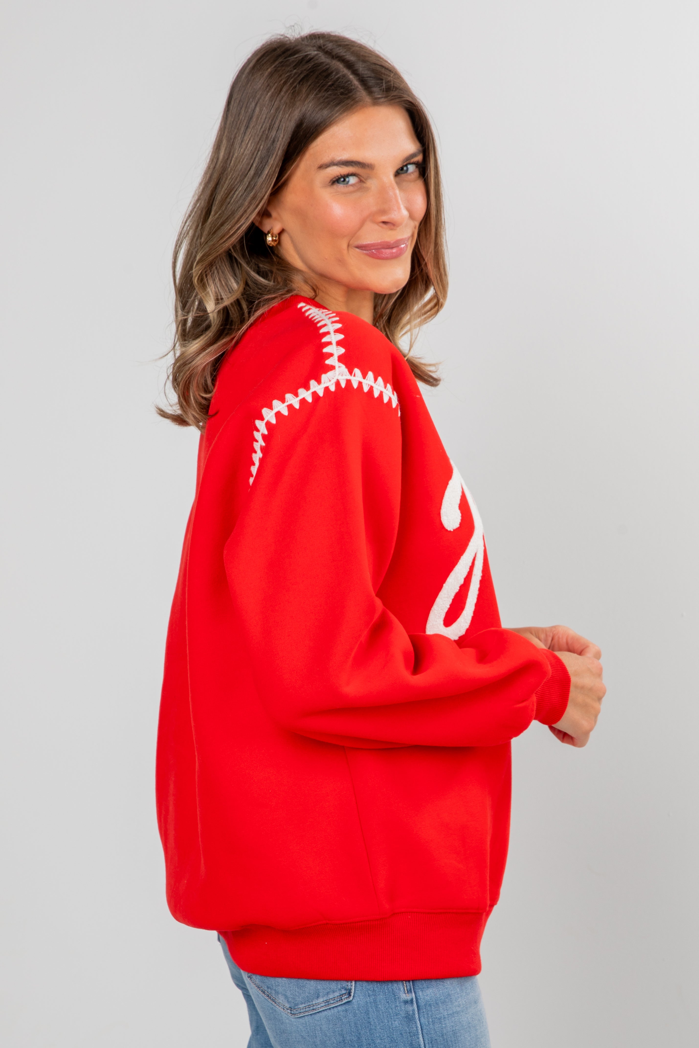Woman wearing a red sweater with white patterns on a gray background