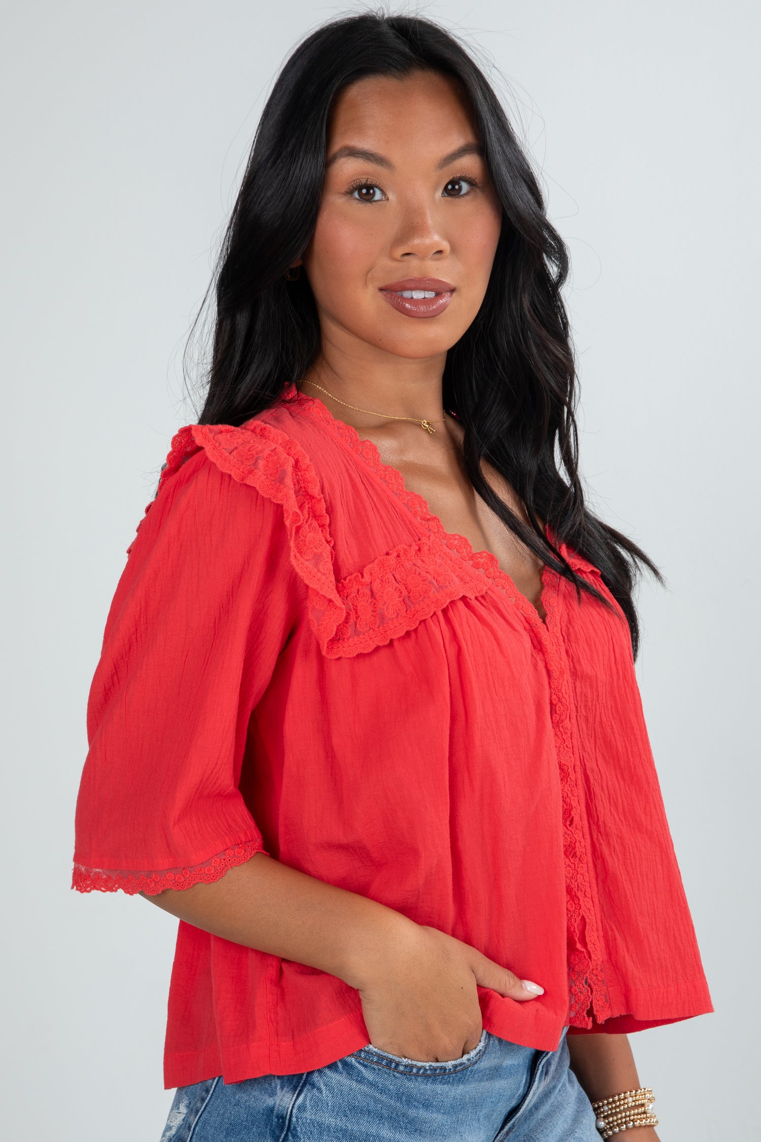 Woman wearing a red blouse with ruffled details on a plain background