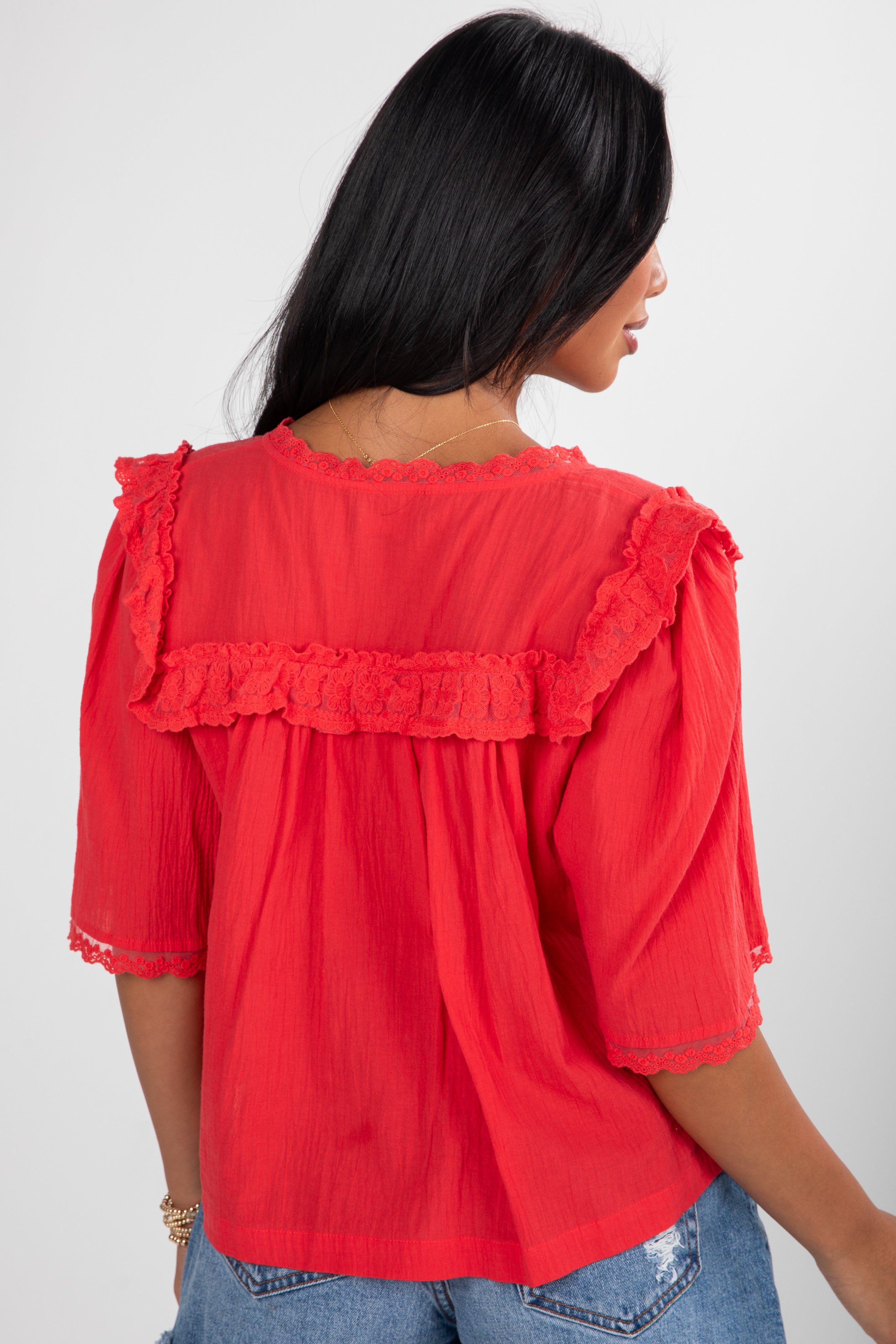 Red blouse with ruffled details worn by a person on a white background