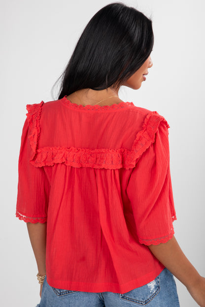 Red blouse with ruffled details worn by a person on a white background